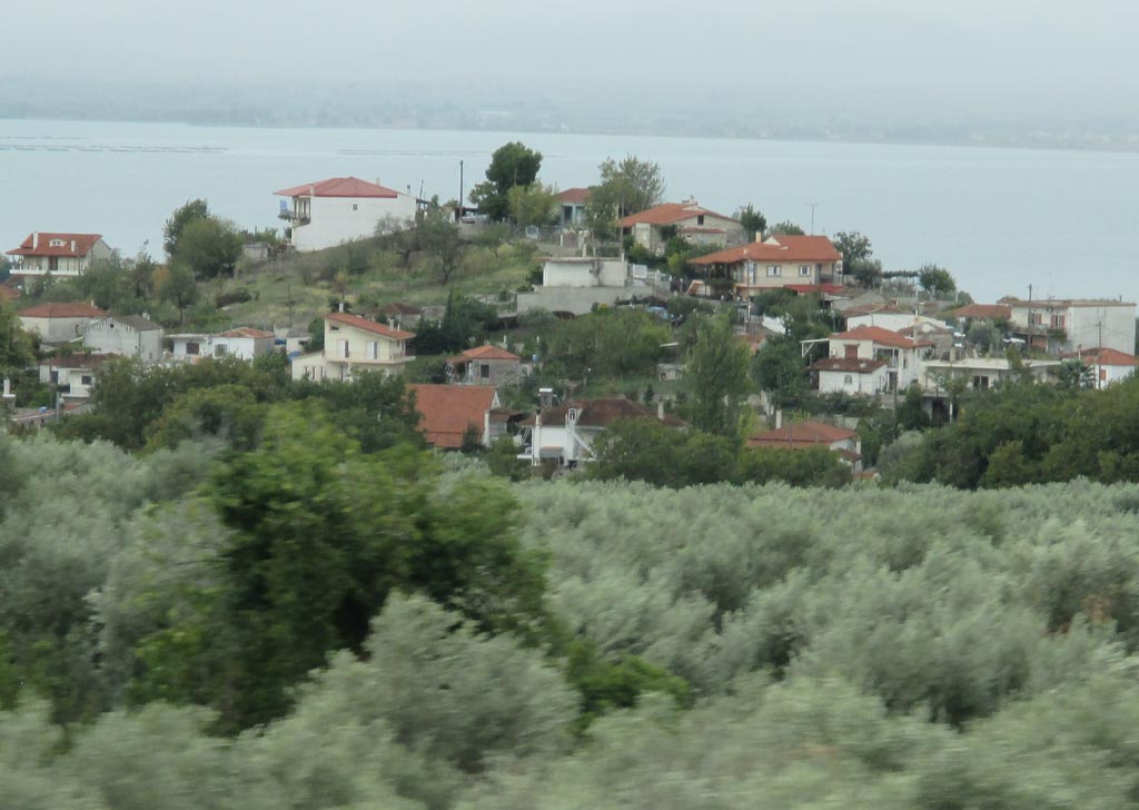 Auf dem Weg nach Velos: Olivenhain, Dorf auf einem Hügel und dahinter die Ägäis.