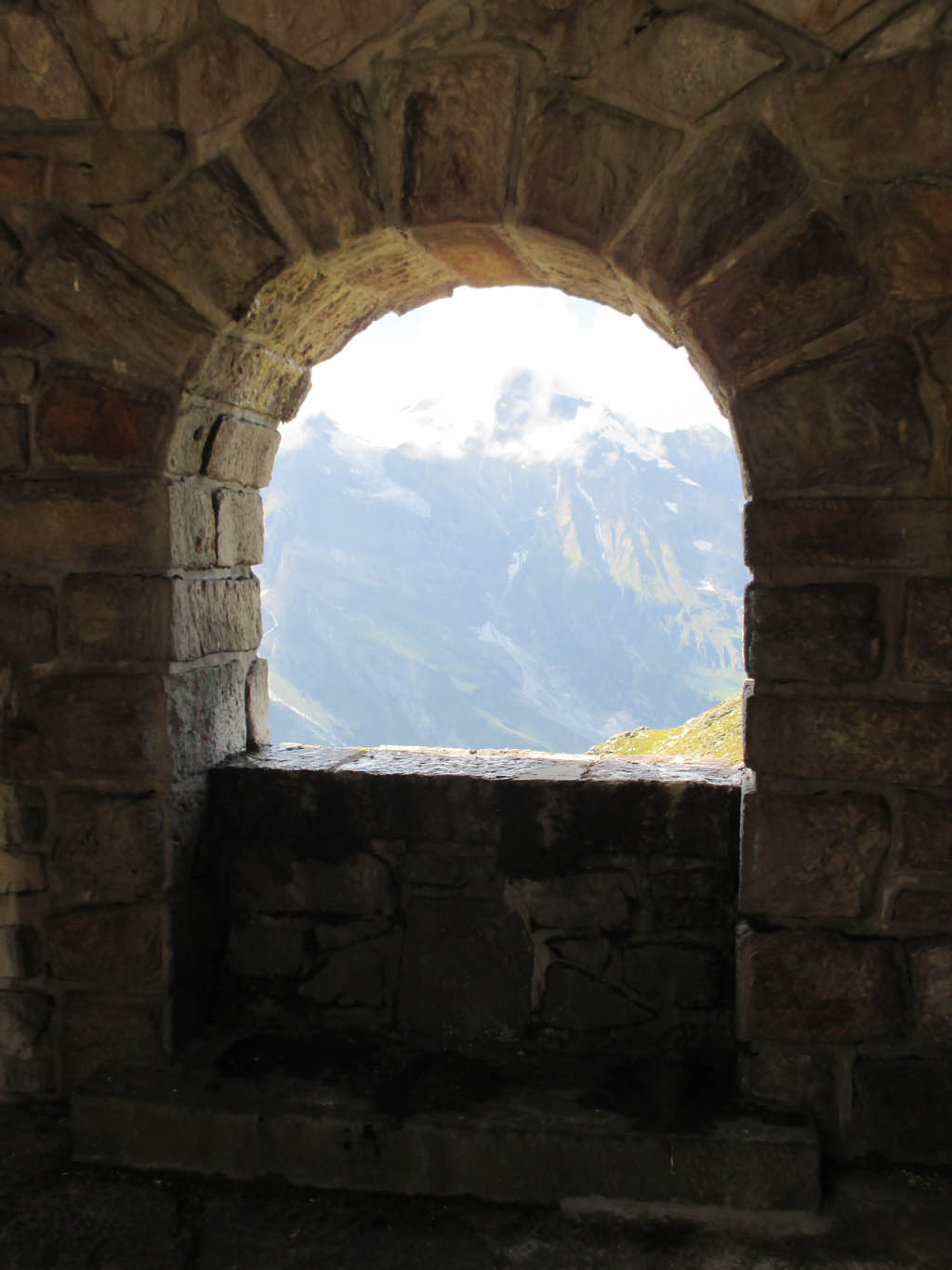 Durch diese Öffnung im Mauerwerk an der Hochalpenstraße geht der Blick Richtung Berge.