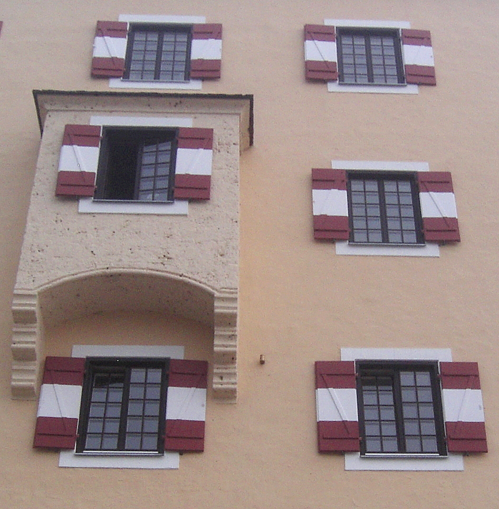 Mit rot-weiß gestreiften Fensterläden: Hausfassade von Schloss Fuschl.