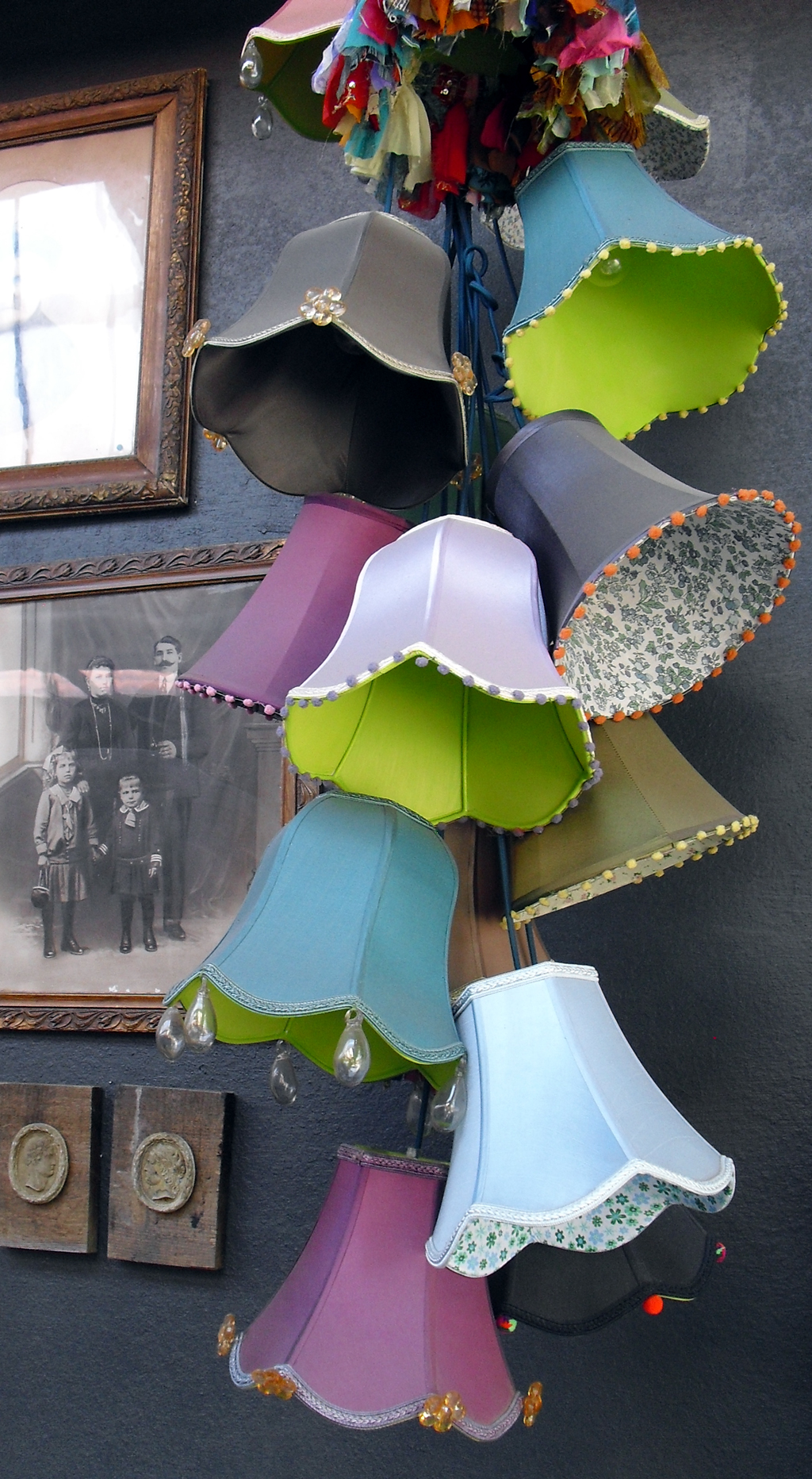 Bunte Lampenleuchter zieren neben alten Fotos die Wand in einem Gebäude der LX Factory.