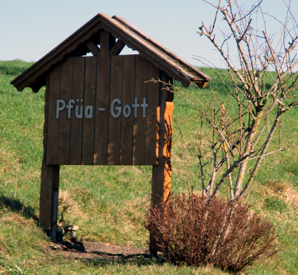 Auf Holz gebannt: Pfüa Gott, der boarische Abschiedsgruaß.