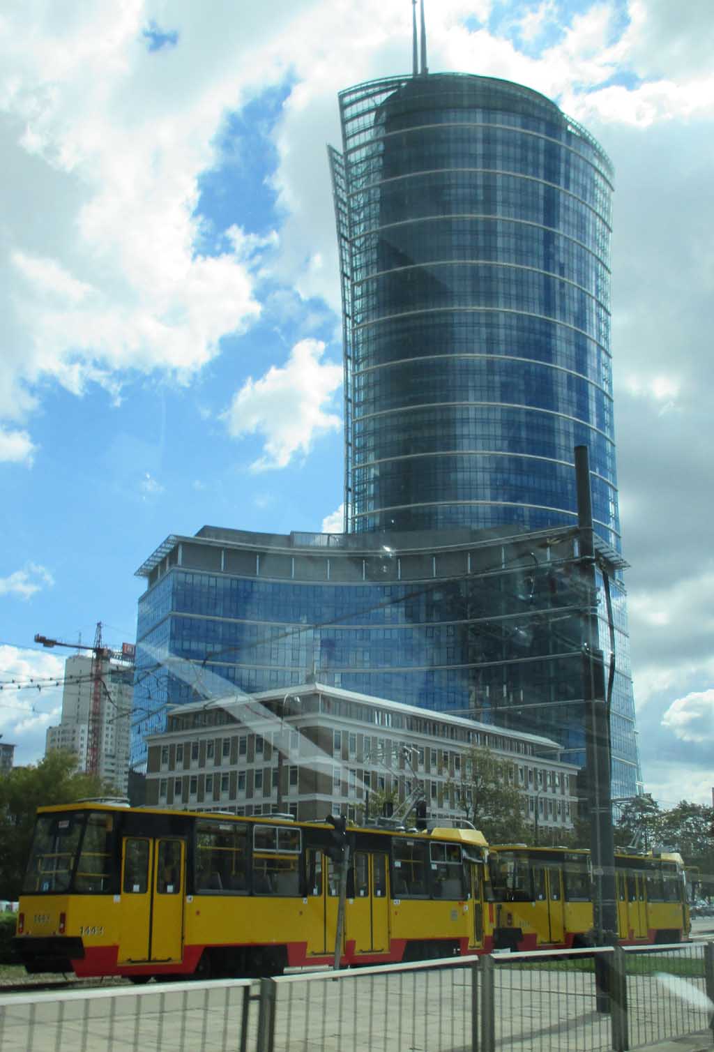 Auf dem Weg zum Flughafen: Straßenbahn vor Hochhaus mit moderner Glasfassade.